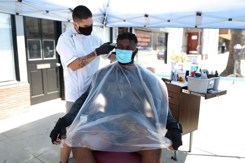 Keith Huerta cuts the hair of Victor Troy, 34, outside Active Barbers on the first day hair salons were allowed to operate outdoor, in Santa Monica, California.  REUTERS/Lucy Nicholson